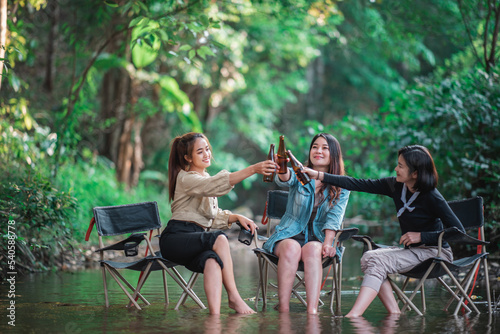 Young women sitting and drink beverage  while camping in forest