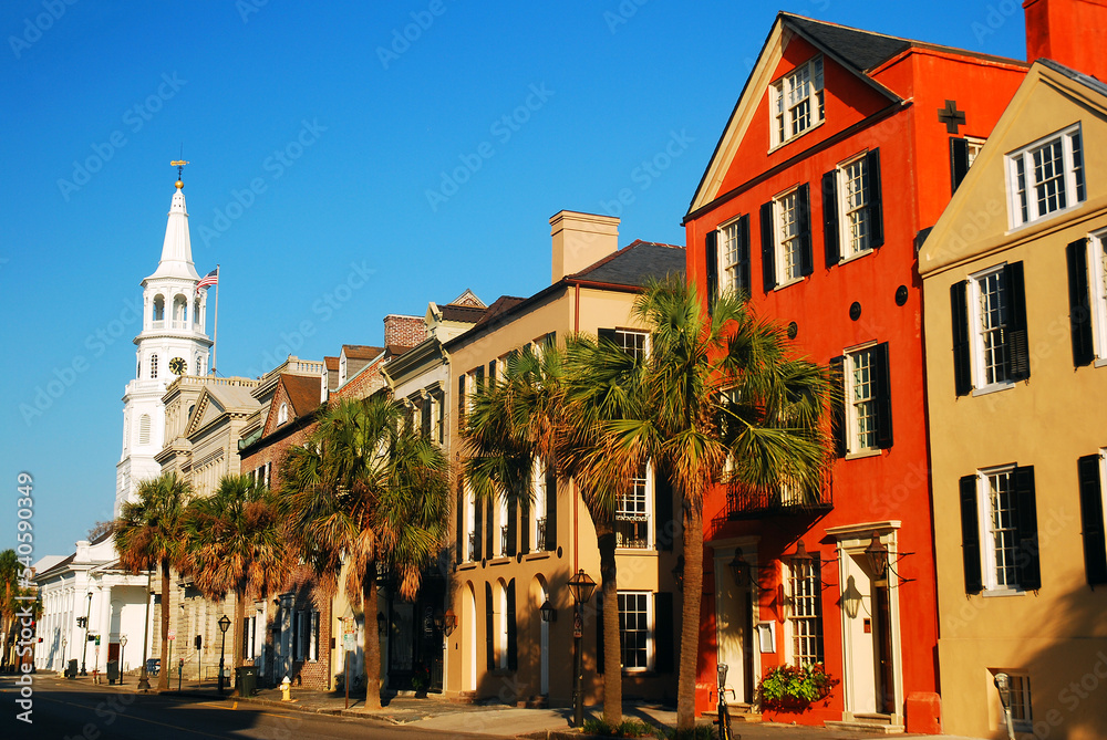Fototapeta premium St Michaels Church stands at the end of a row of colorful homes in the downtown area of Charleston, South Carolina
