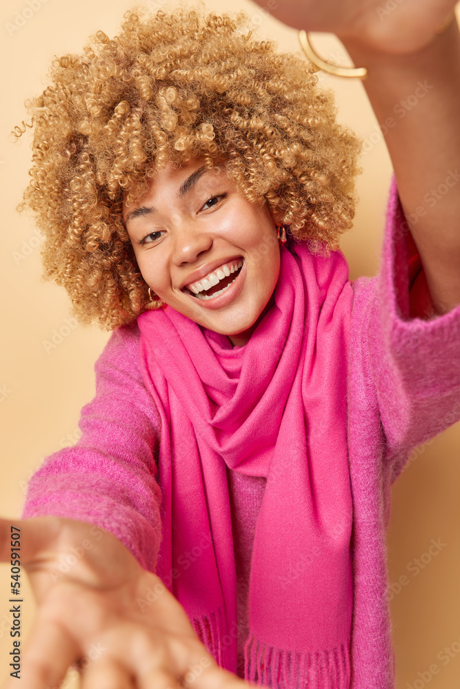 Positive friendly woman stretches arms and hands wants to hug you smiles toothily wears casual pink jumper and scarf around neck welcomes friend isolated over beige background wants to hold something Positive friendly woman stretches arms and hands wants to hug you smiles toothily wears casual pink jumper and scarf around neck welcomes friend isolated over beige background wants to hold something