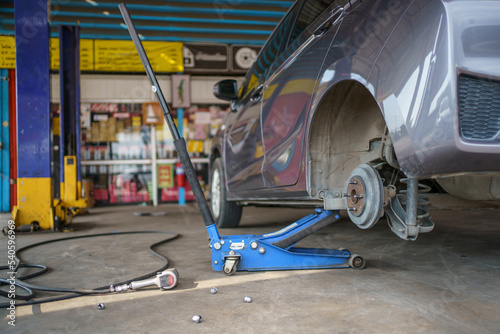 Technician or repairman using a hydraulic jack lift up a car at rear wheel to changing a flat tyre.