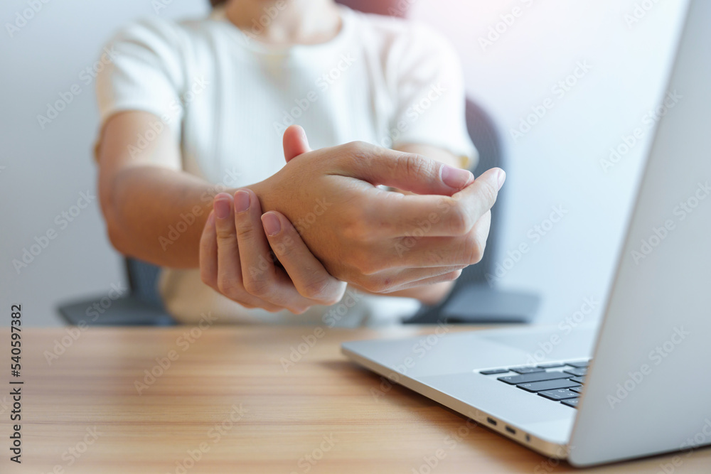 Woman having wrist pain when using laptop computer and mouse during working long time on