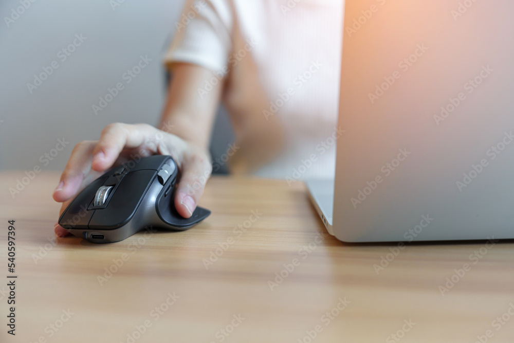 Fototapeta premium woman hand using ergonomic vertical mouse during working on Adjustable desk, prevention wrist pain. De Quervain s tenosynovitis, Intersection Symptom, Carpal Tunnel or Office syndrome concept