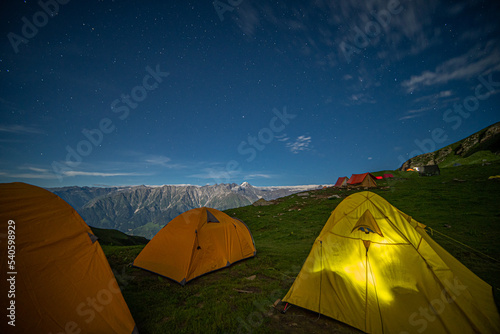 Night camping on mountain with sky and stars on green grass at Manali, India.
