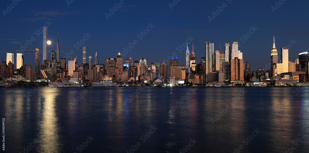 New York City skyline at night including the moon and nice reflection into Hudson River, USA