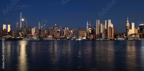 New York City skyline at night including the moon and nice reflection into Hudson River  USA
