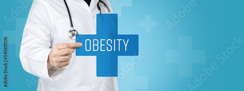 Obesity. Doctor holding blue cross with medical term on it.