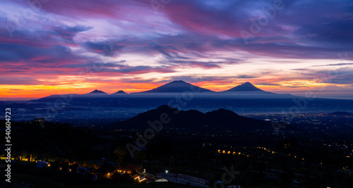Beautiful colorful epic sunrise sky with mountain range and beautiful city lights, Magelang City and Merapi, Merbabu, Andong, Telomoyo mountain looking out from Sumbing Mountain - Mangli Village photo