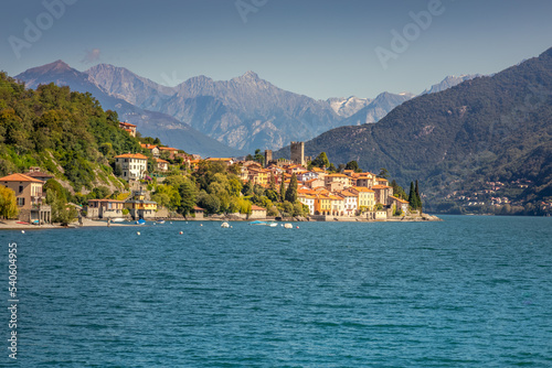 Idyllic Lake Como coastline with village and speedboat at sunny day, Italy