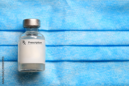 Prescription medical vial of injectable medicine on a blue medical mask.
