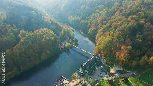 Recreation area near Grodno castle in Zagorze, Poland. Beaituful autumn landscape with mountains covered with forest, river and bridge for people over it photo