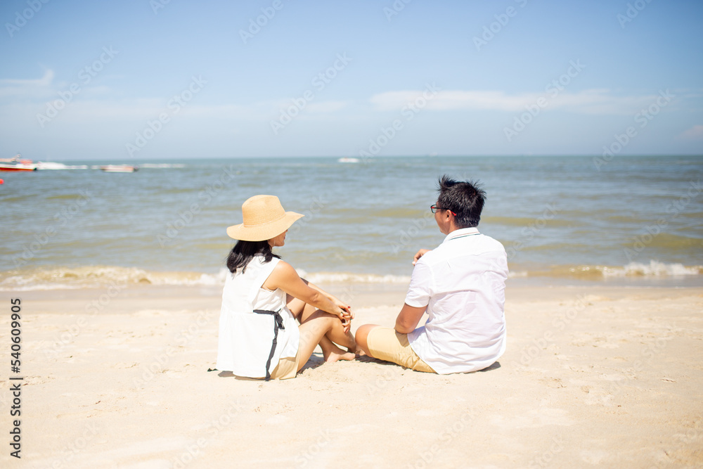 beautiful couple sit on the sand and looking at the camera