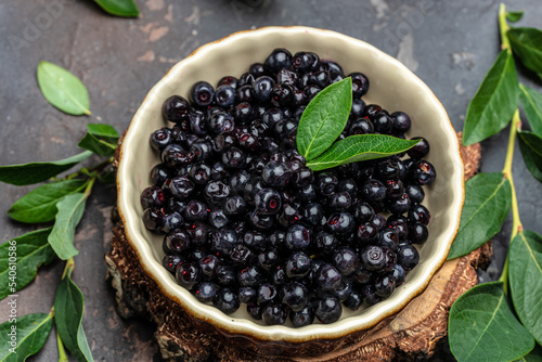 Superfoods antioxidant of indian mapuche. Bowl of fresh maqui berry on dark background, top view photo