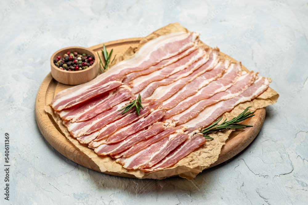 Close up Bacon slices. Pig meat. Pork belly with rosemary on a wooden board, Keto diet food ingredients. Restaurant menu, dieting, cookbook recipe