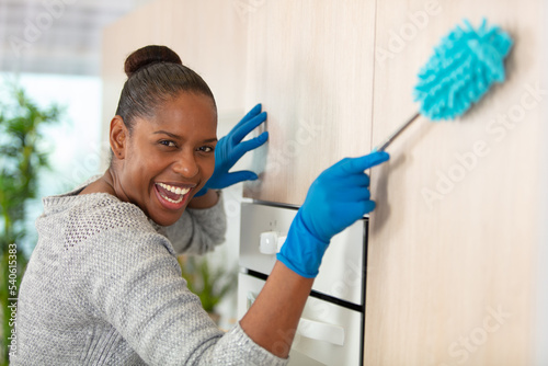 joyful housemaid holding a brush to dust photo