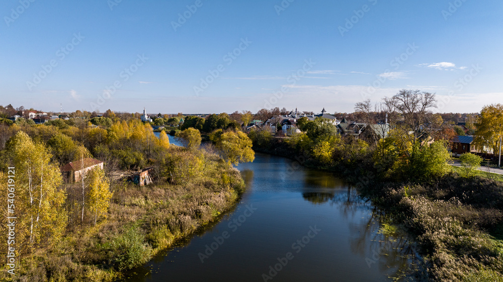 Fototapeta premium panoramic view from a drone of ancient buildings and fields and forests against the backdrop of autumn colors in Suzdal
