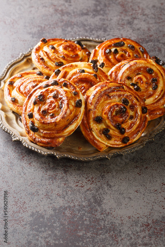 Pain aux Raisins, Danish raisin pastry swirls closeup in the plate on the table. Vertical photo