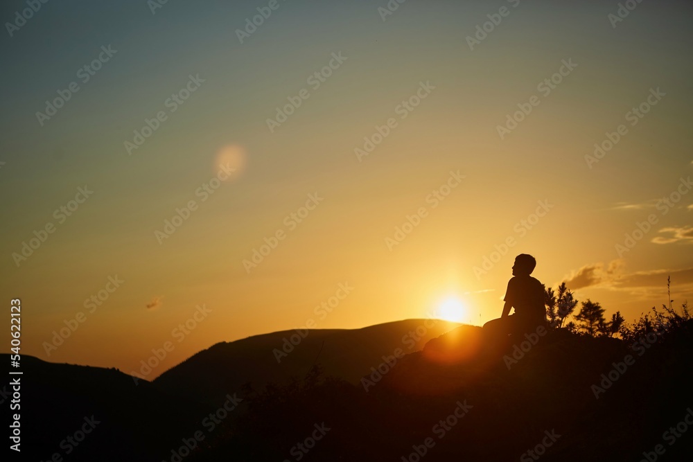 The silhouette of a man against the sunset in the mountains. Yellow colors of nature. The concept of travel