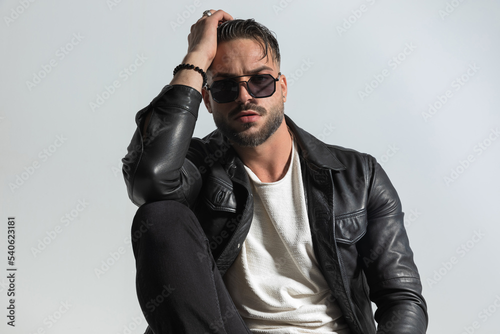 confident bearded man wearing cool leather jacket and sunglasses confident bearded man wearing cool leather jacket and sunglasses