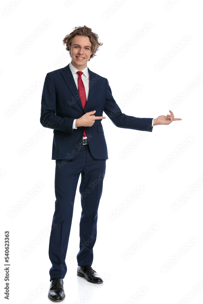 modern businessman with curly hair pointing fingers to side and smiling modern businessman with curly hair pointing fingers to side and smiling