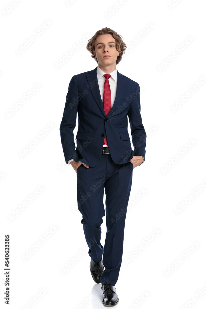 confident businessman in suit being cool and walking with hands in pockets confident businessman in suit being cool and walking with hands in pockets