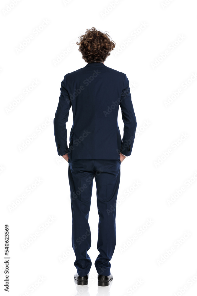 back view of elegant young businessman holding hands in pockets back view of elegant young businessman holding hands in pockets