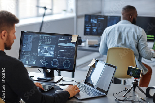 Portrait of male programmer or data specialist using computer in office with charts on screen, copy space