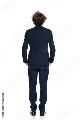 back view of elegant young businessman holding hands in pockets