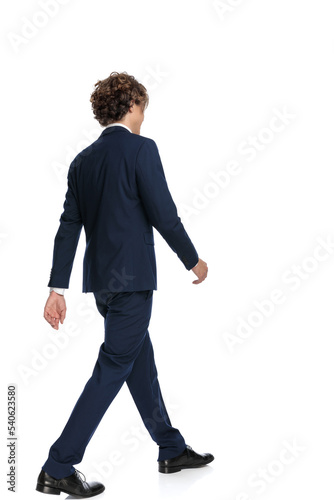 rear view of elegant young businessman with long hair stepping