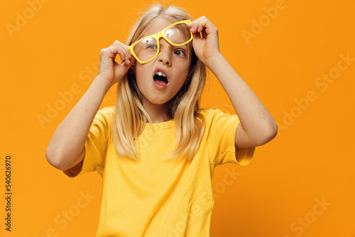 portrait of a cute girl in yellow clothes putting on yellow glasses for sight
