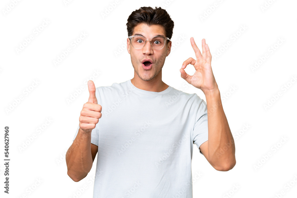 Young caucasian handsome man over isolated background showing ok sign and thumb up gesture Young caucasian handsome man over isolated background showing ok sign and thumb up gesture
