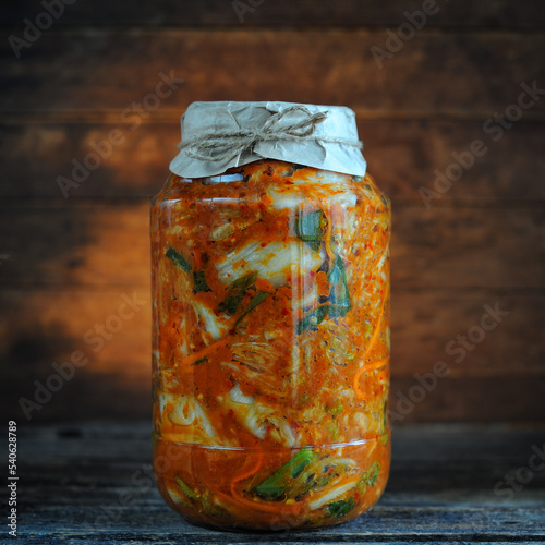 Homemade kimchi cabbage in a glass jar on a wooden table