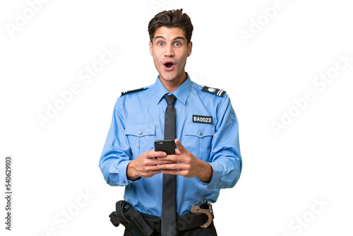 Young police man over isolated background surprised and sending a message