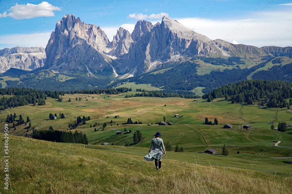 Young traveller woman enoys the view into the spectacular dolomite mountains: disctinctive sassolungo group. travel and adventure concept.
