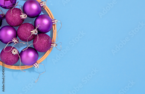 Purple Christmas tree decoration balls in wooden circle on cyan background..