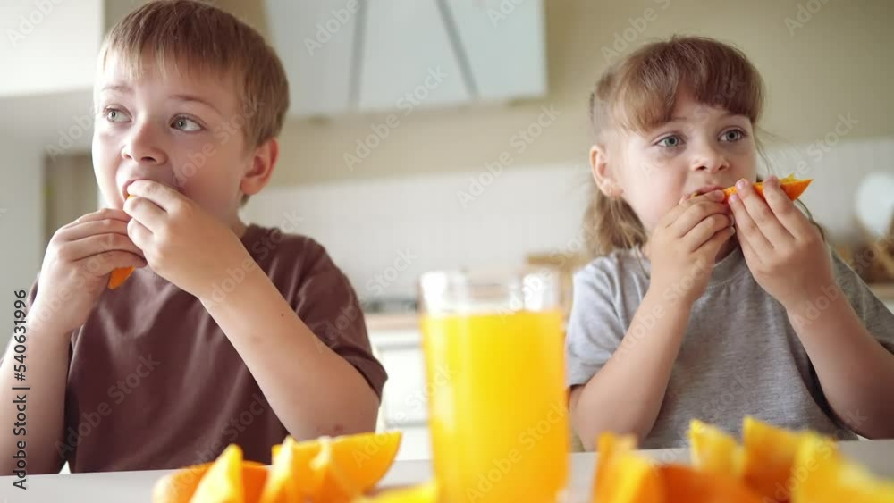 children eat oranges. happy family a kid dream concept. drinking fresh juices. morning breakfast brother and sister eat oranges in the kitchen. lifestyle fruits orange juice healthy eating children eat oranges. happy family a kid dream concept. drinking fresh juices. morning breakfast brother and sister eat oranges in the kitchen. lifestyle fruits orange juice healthy eating