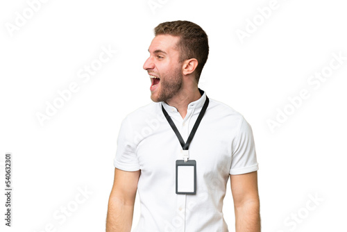 Young caucasian man with ID card isolated on green chroma background laughing in lateral position © luismolinero