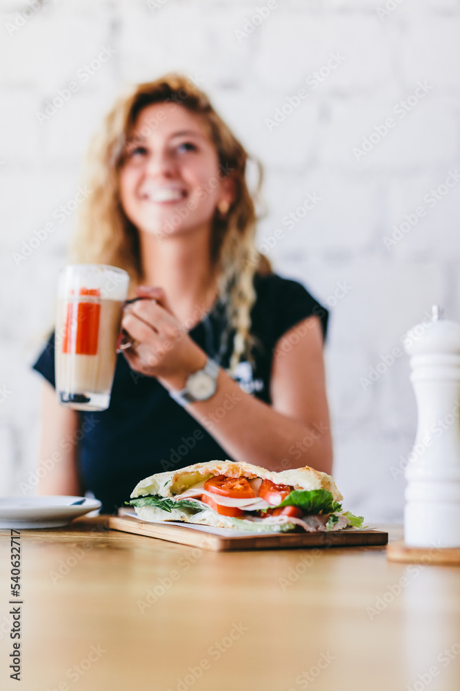 Woman having breakfast in restaurant with coffee and sandwich Woman having breakfast in restaurant with coffee and sandwich