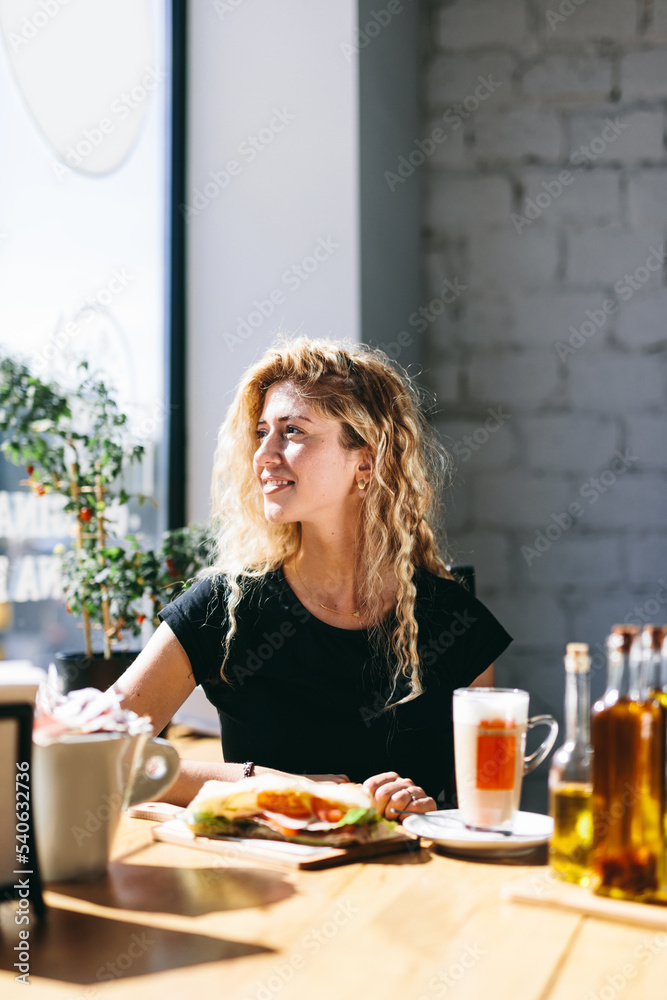 Woman having breakfast in restaurant with coffee and sandwich