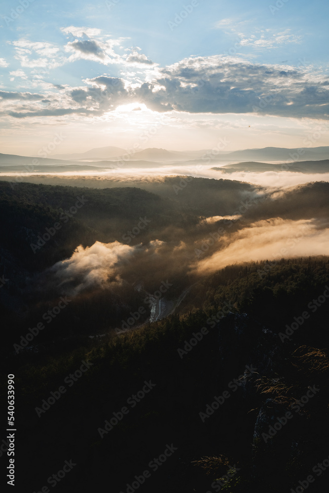 Sunrise in the mountains, Aigir view from the top of the mountain to the river valley, Bashkortostan nature of Russia, the Ural Mountains, fog in the morning creeps below. Sunrise in the mountains, Aigir view from the top of the mountain to the river valley, Bashkortostan nature of Russia, the Ural Mountains, fog in the morning creeps below.