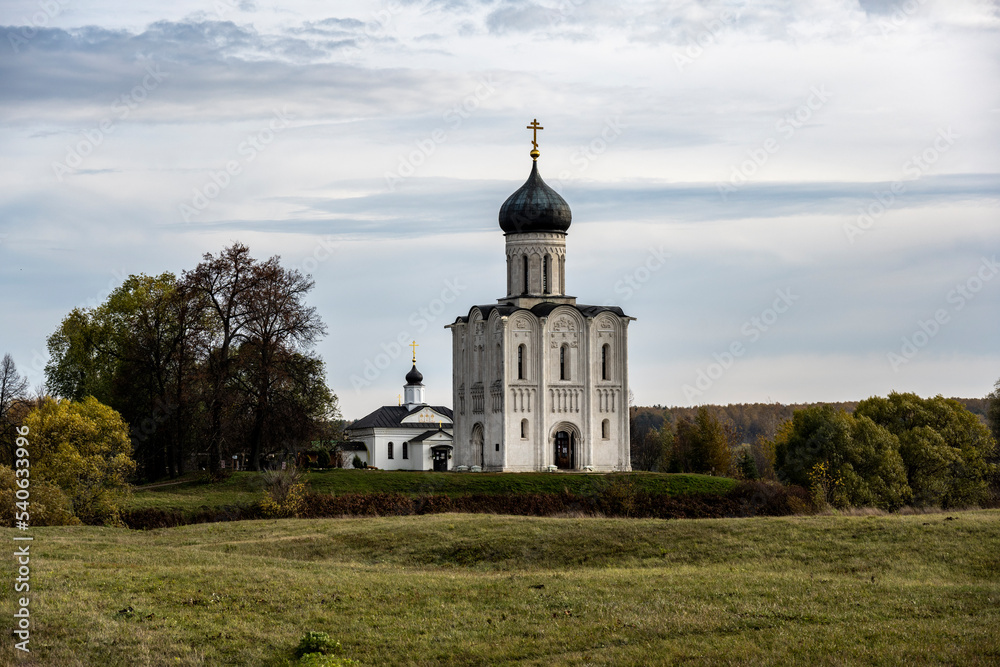 white-stone church in the field against the backdrop of autumn nature