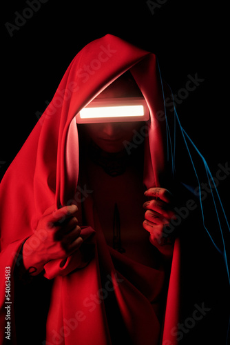 Portrait of man in red mantle with innovation glasses standing against black background photo