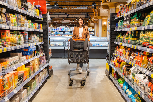 Wallpaper Mural a woman with a cart walks between rows of shelves in a grocery store Torontodigital.ca