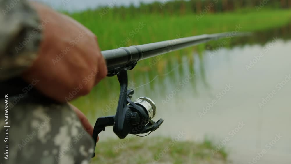 Close-up of a fisherman's hands while fishing near the shore on the lake Close-up of a fisherman's hands while fishing near the shore on the lake