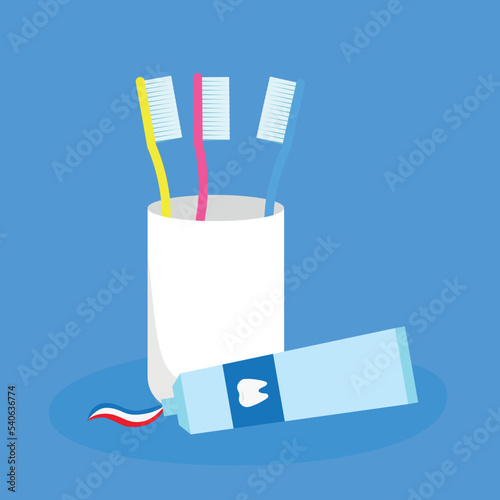 A glass with three toothbrushes and a tube of toothpaste
