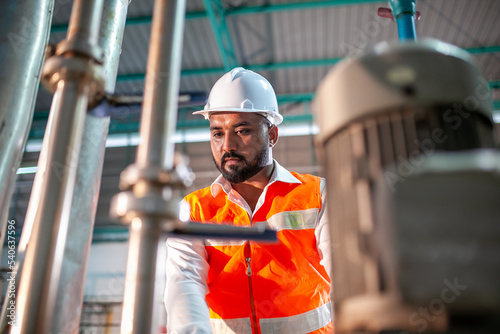 professional technician engineer with safety hard hat working to maintenance construction equipment in industrial factory, worker is checking or repair the machine.