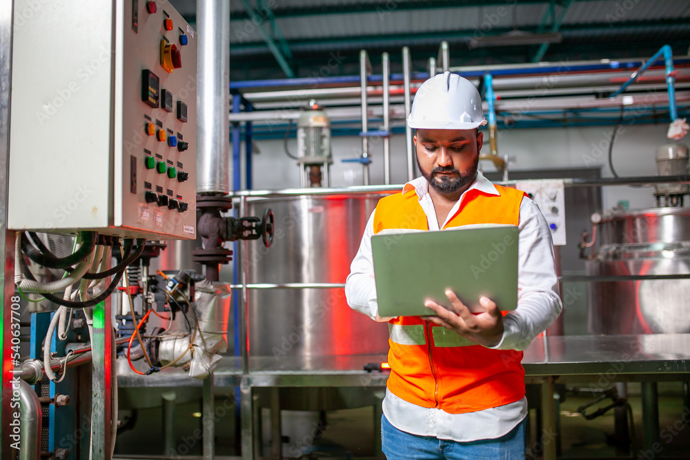 Professional engineers with helmets work to maintain industrial construction equipment, workers are inspecting or repairing machines with laptop. Professional engineers with helmets work to maintain industrial construction equipment, workers are inspecting or repairing machines with laptop.
