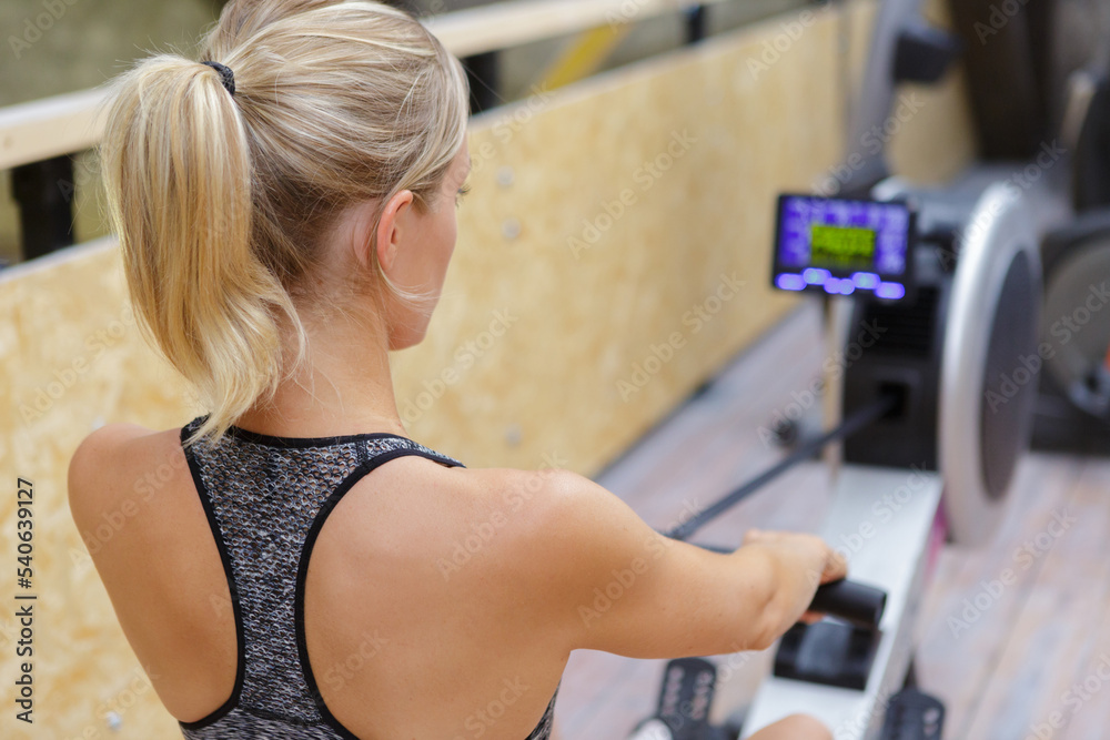 Obraz premium woman athlete exercising on rowing machine