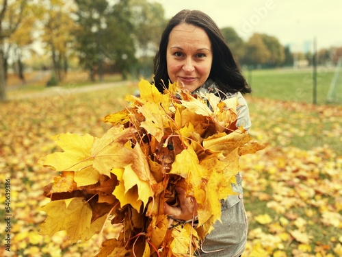 A woman smelling autumn maple leaves relaxation on nature