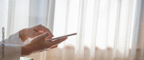 Photography A woman playing with your smartphone by the window in the room
