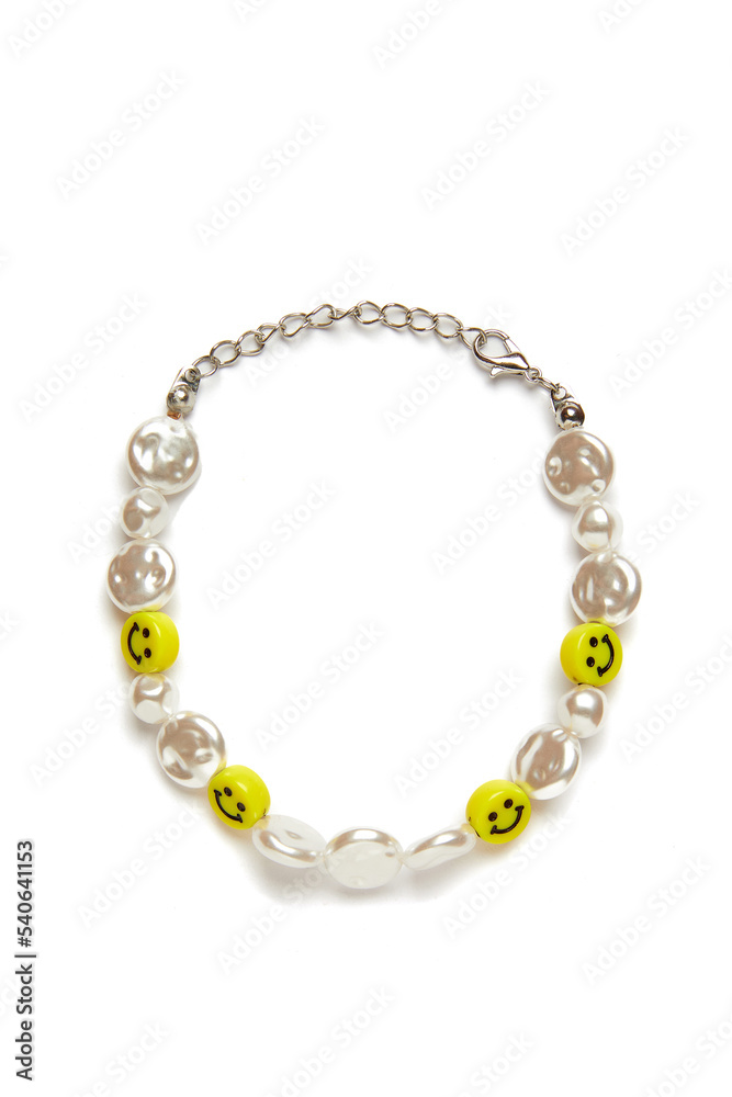 Detail shot of a shiny bracelet made out of pearl beads and yellow smileys. The stylish elegant bracelet with a lobster clasp is isolated on the white background. Detail shot of a shiny bracelet made out of pearl beads and yellow smileys. The stylish elegant bracelet with a lobster clasp is isolated on the white background.
